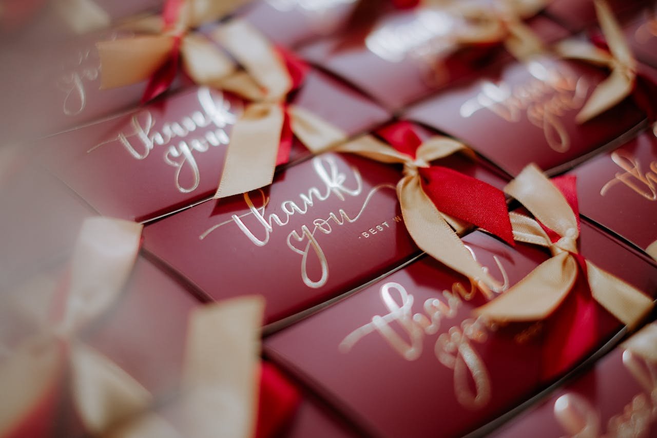 A close-up of beautifully wrapped red gift boxes with 'Thank you' tags and golden ribbons.